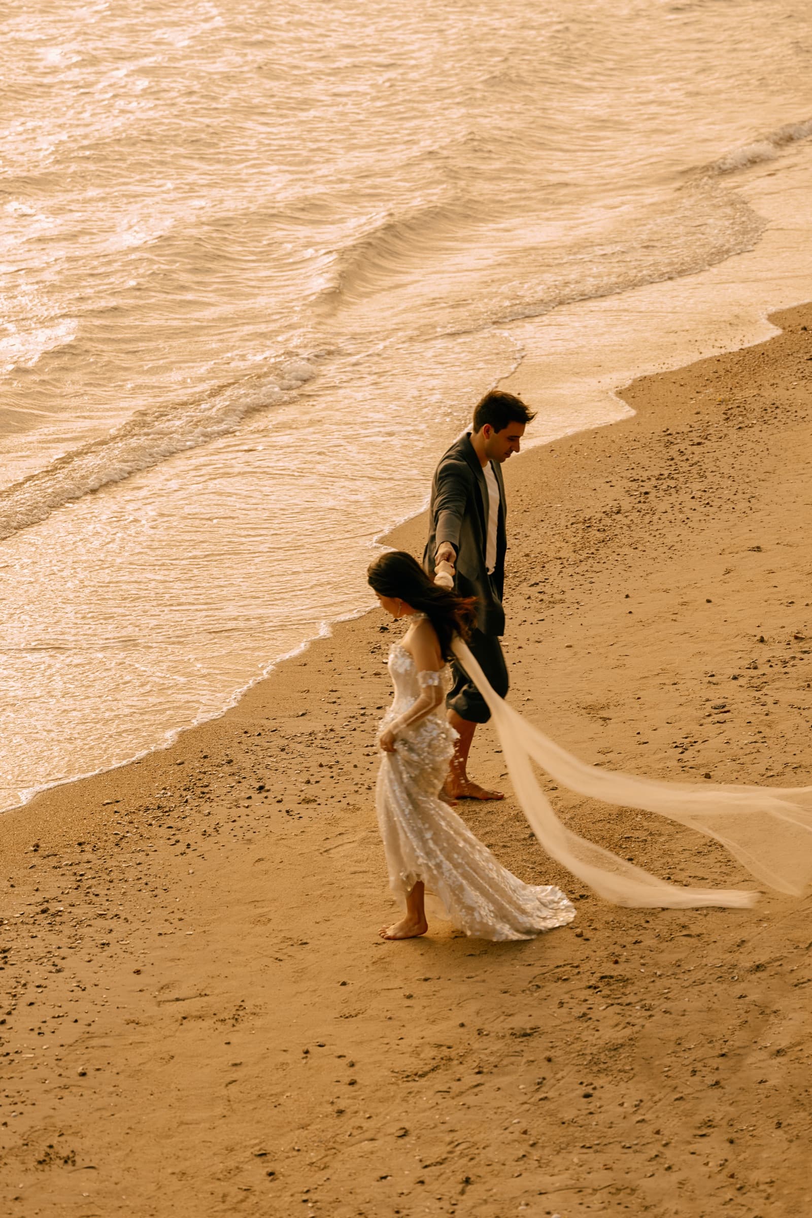 The couple walking together along the shoreline at dusk