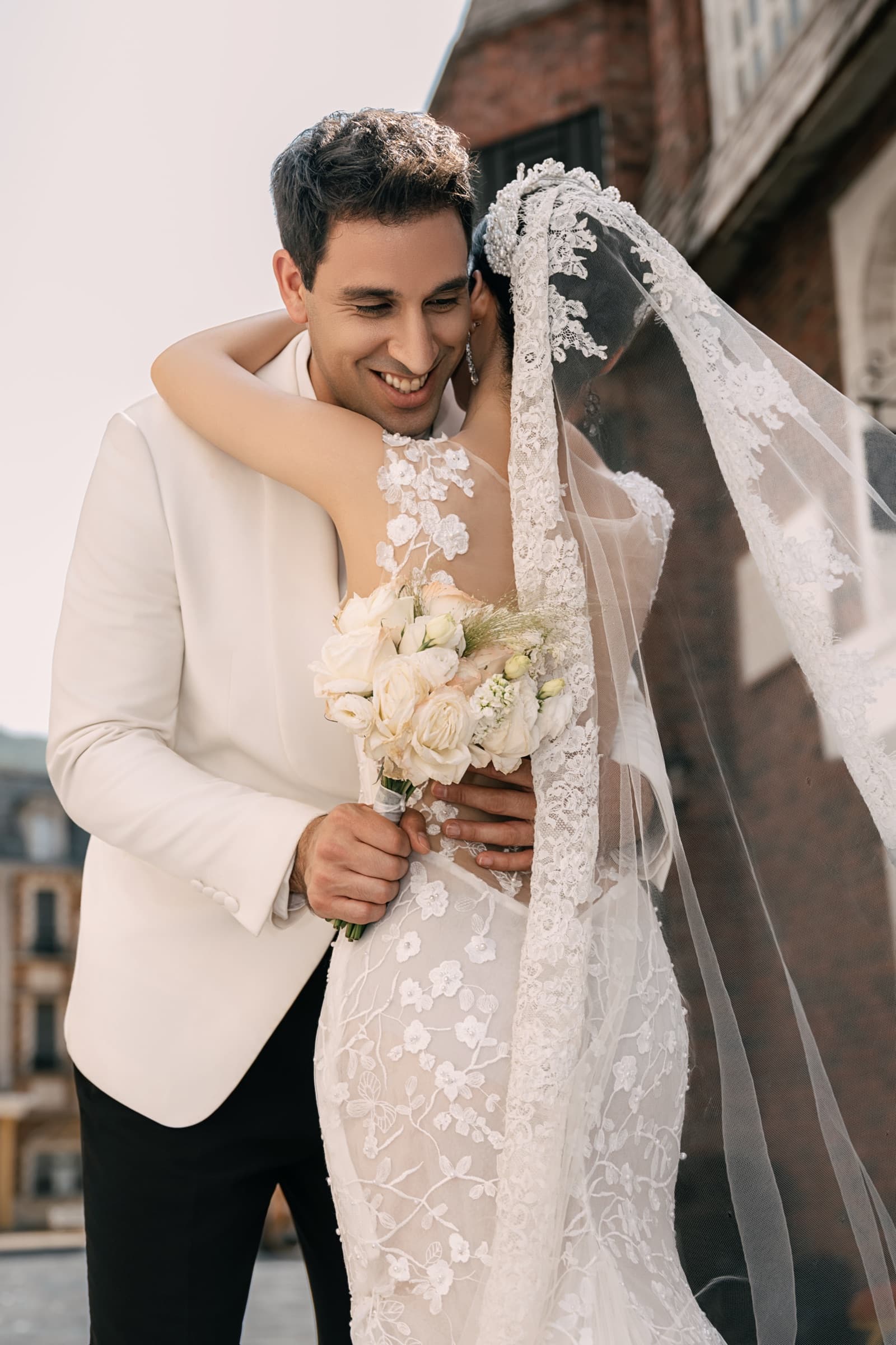 The groom embracing his bride, bouquet in hand