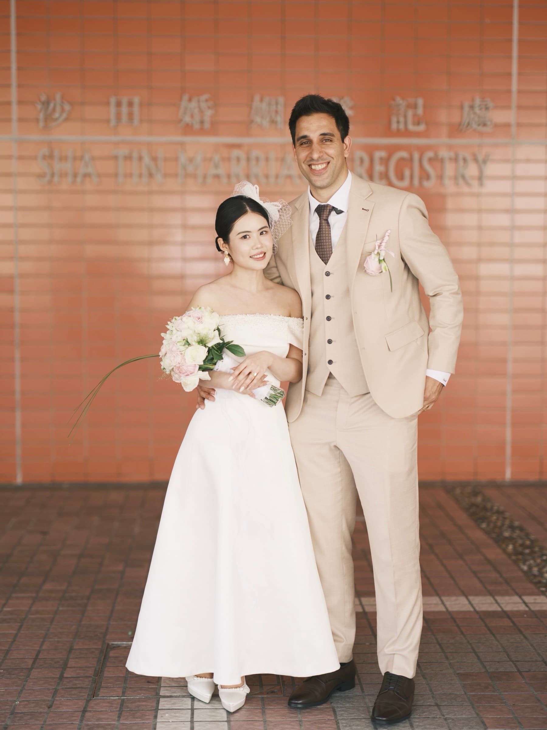The couple smiling outside the marriage registry on their wedding day